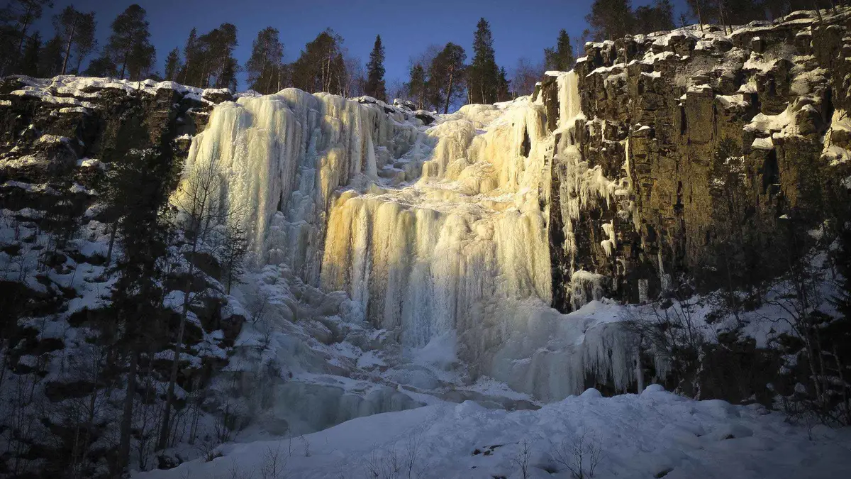Guided group walking the frozen river bed between canyon walls on a Korouoma frozen waterfalls tour from Rovaniemi