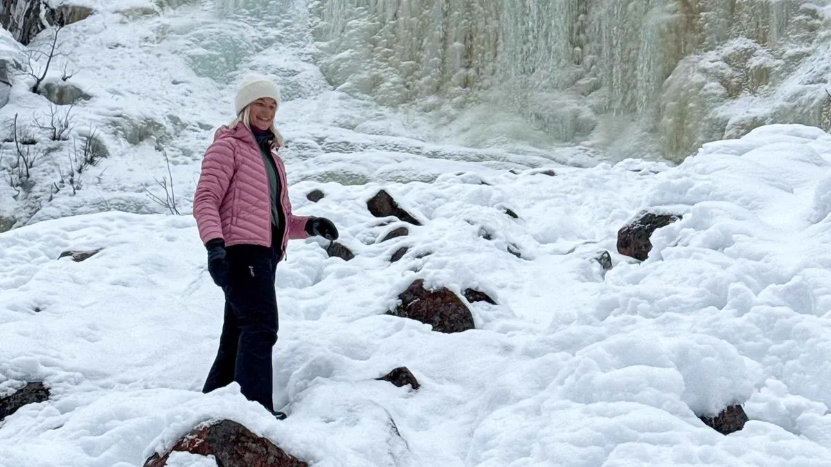 Guide and two travellers pausing below a blue ice column on a private Korouoma Canyon frozen waterfall hike, Lapland